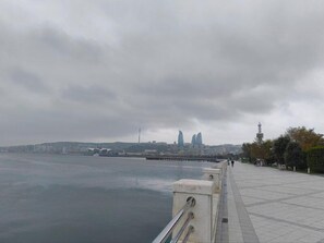 A waterfront promenade with a view of a city skyline, including a tower and modern buildings. - Deluxe City Hotel (Baku)