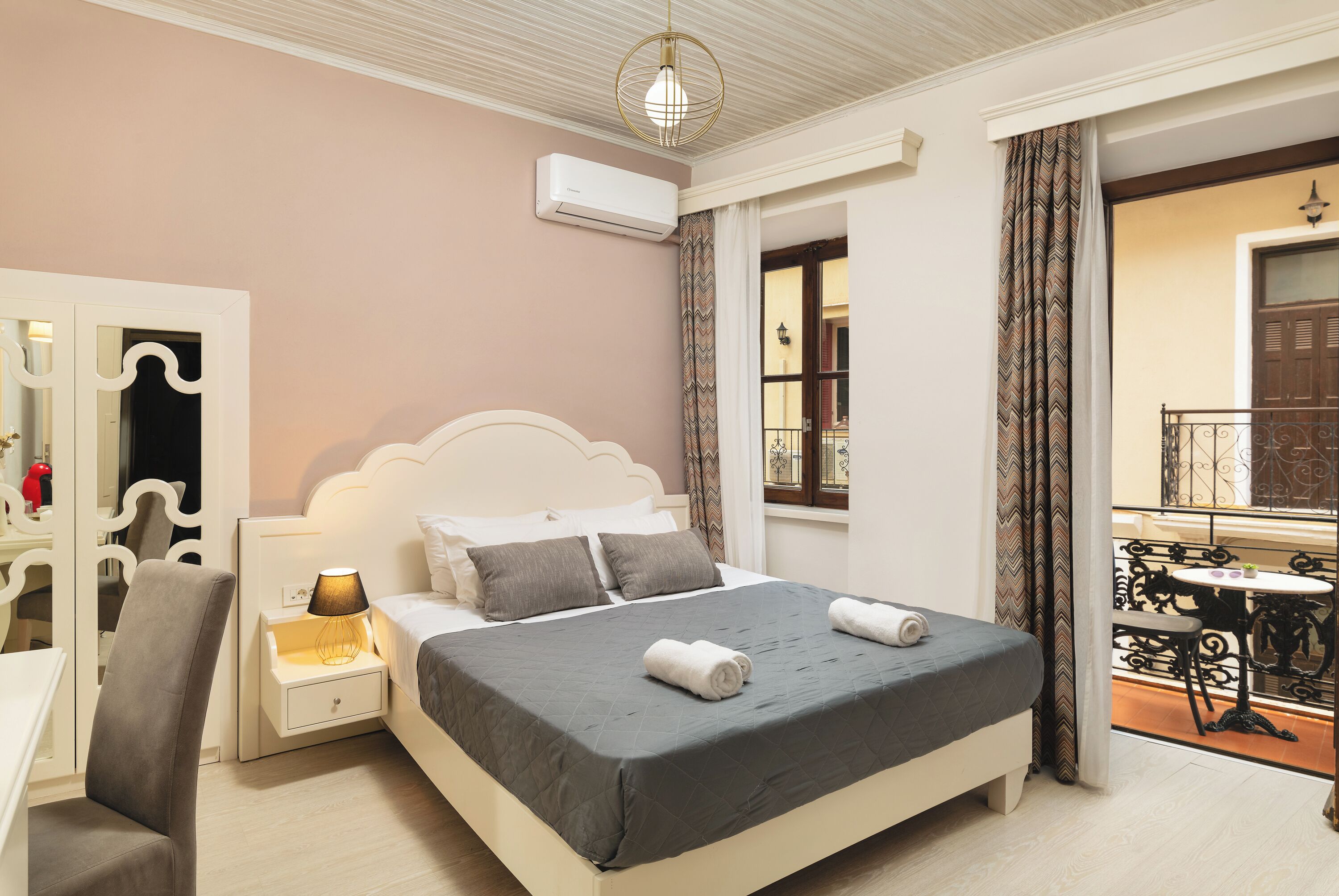 A bedroom with a bed, bedside table, lamp, and a view of the balcony.