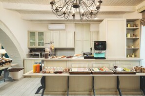 A modern kitchen with a coffee machine, breakfast bar, and various food items. - Elia Palazzo Hotel (Chania)