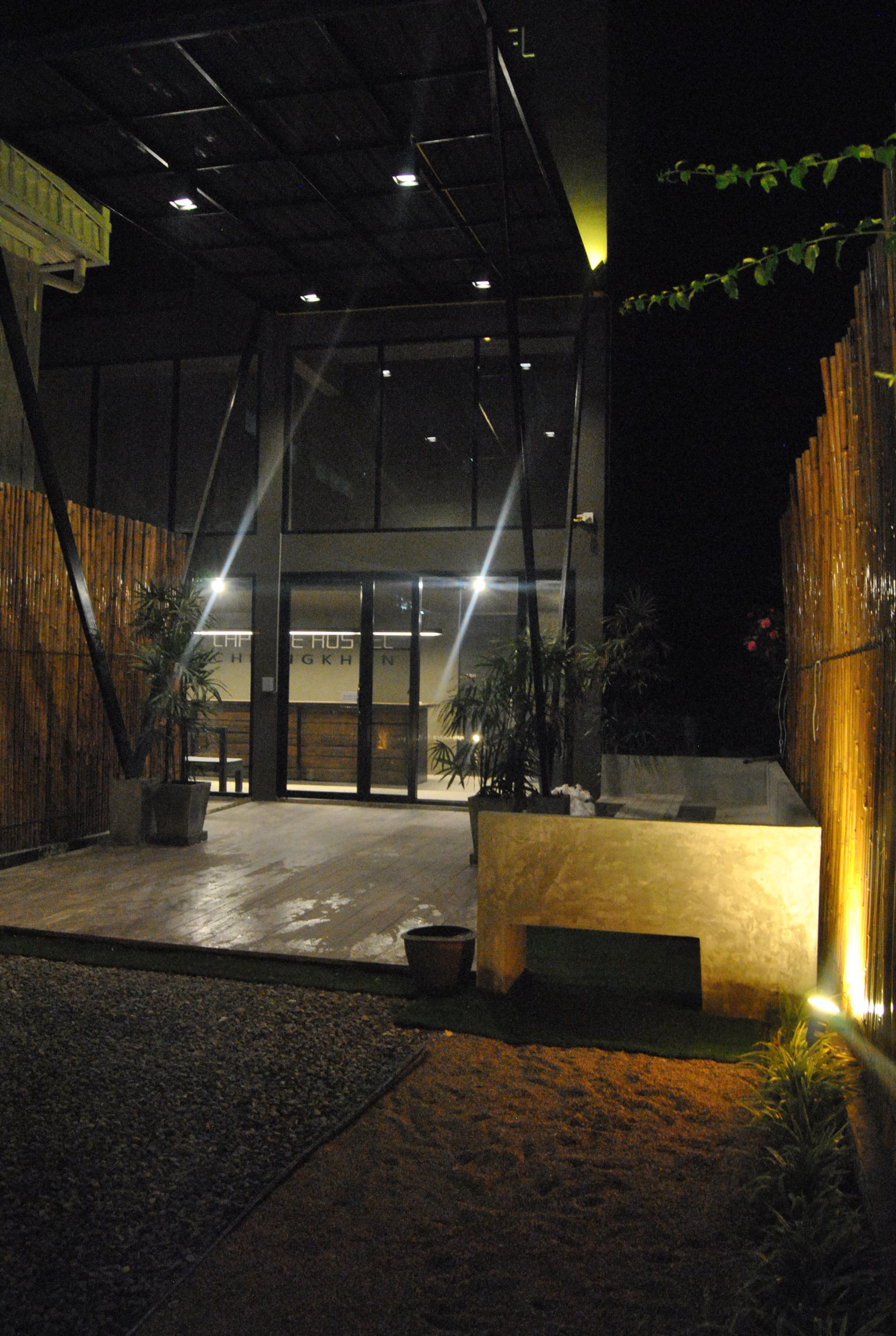 An indoor entrance with a reception desk, potted plants, and a wooden fence. - Capsule Hostel Chiangkhan (Chiang Khan)