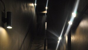 A dimly lit staircase with a handrail, surrounded by walls and a light fixture at the top. - Capsule Hostel Chiangkhan (Chiang Khan)
