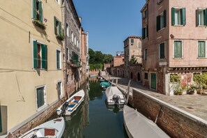 Un canal estrecho con barcos amarrados a ambos lados, bordeado por edificios con contraventanas verdes y balcones.
