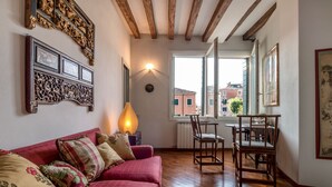 Una habitación acogedora con un sofá rojo, piso de madera y un comedor con sillas y una mesa.