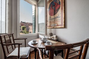 Un comedor con una mesa redonda, dos sillas, un hervidor de tetera y una taza. Un cuadro enmarcado cuelga de la pared.