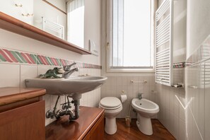 A bathroom with a wooden vanity, a sink, a toilet, and a bidet. - 7 Windows on Venice (Venice)