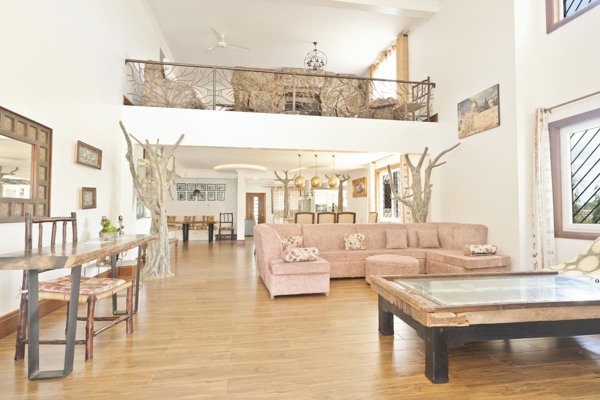 Un salón espacioso con una mesa de comedor de madera, un sofá seccional rosa y una mesa de centro de vidrio.