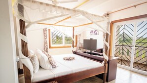 Een slaapkamer met hemelbed, een televisie en uitzicht op de omgeving door een groot raam.