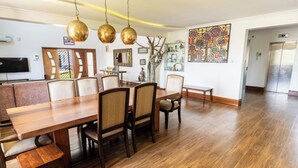 Een eetgedeelte met een houten tafel en stoelen, een kroonluchter en een decoratief wandobject.