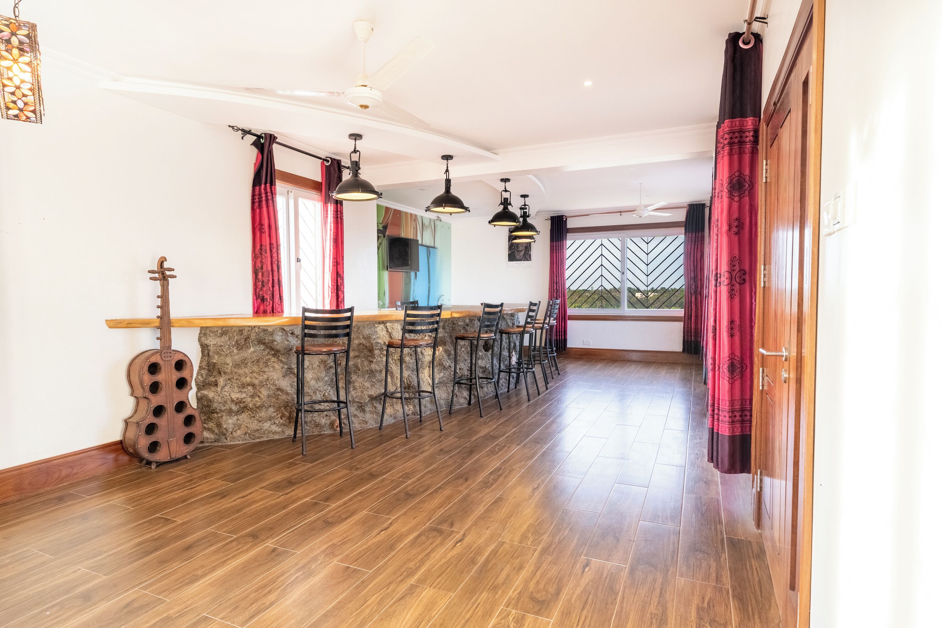 A spacious kitchen with a long counter, multiple bar stools, and a guitar leaning against the wall.