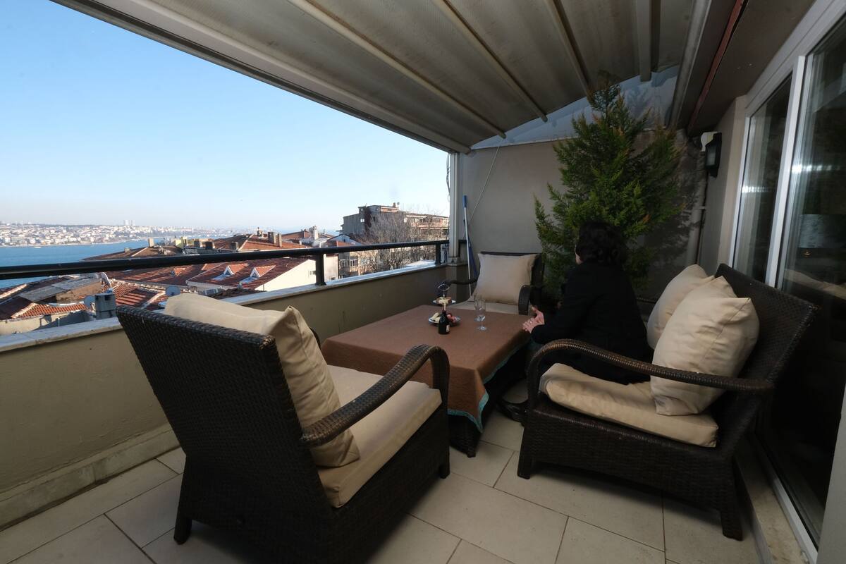 Un balcon agrémenté de meubles en osier, d’une table et d’une plante en pot.