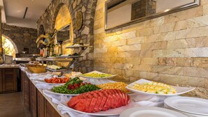 Een buffet met diverse gerechten en een achtergrond van een stenen muur.