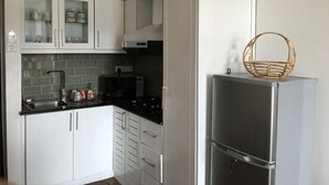 A modern kitchen with white cabinets, a stainless steel refrigerator, and a microwave.