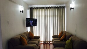 A living room with two sofas, a small table, and a TV on the wall.