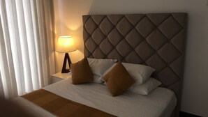 A neatly made bed with a tufted headboard, a bedside lamp, and two pillows.
