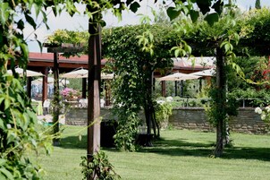 Un jardín con pérgola, muro de piedra y zona de estar al aire libre.