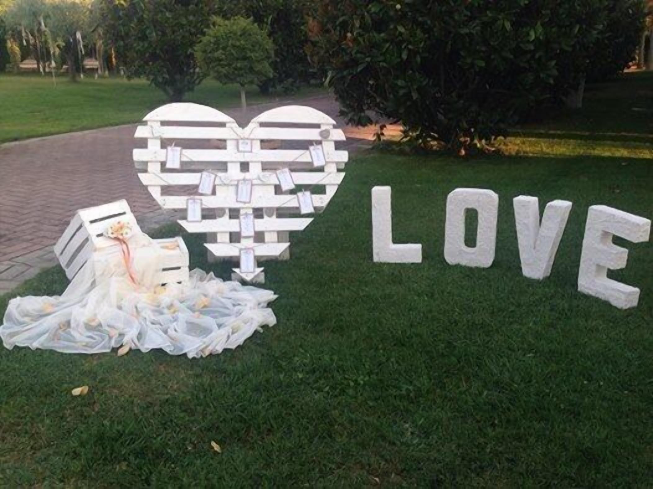 A heart-shaped decoration with the word LOVE next to it on a grassy area.