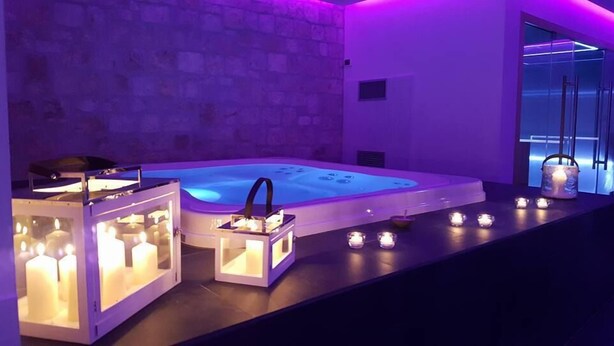 Un área de spa con un jacuzzi, velas y una pared de piedra.