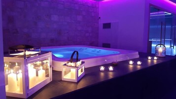 Un área de spa con un jacuzzi, velas y una pared de piedra.