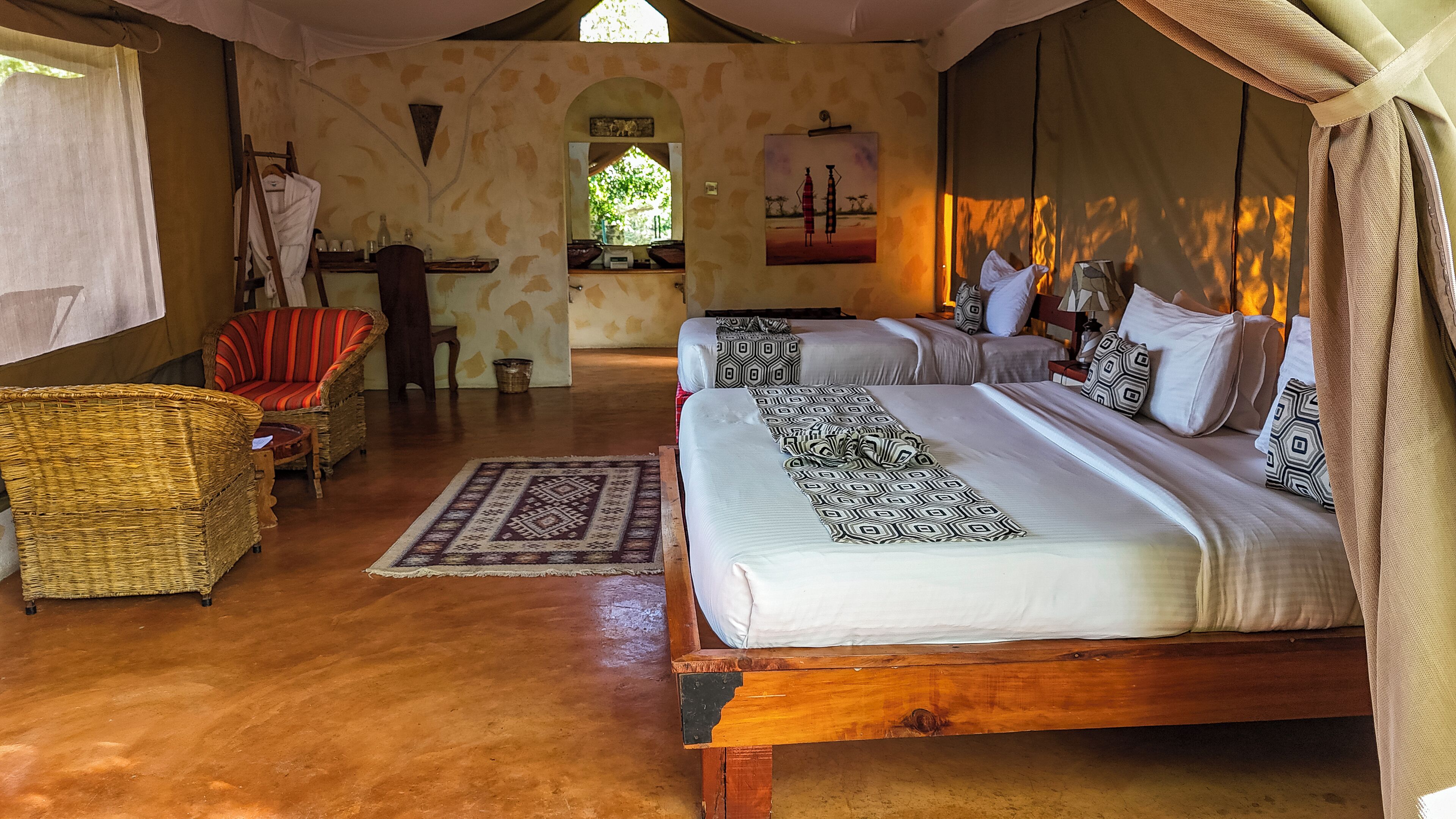 Una habitación amplia con una cama grande, una silla de mimbre y una mesita con un espejo.
