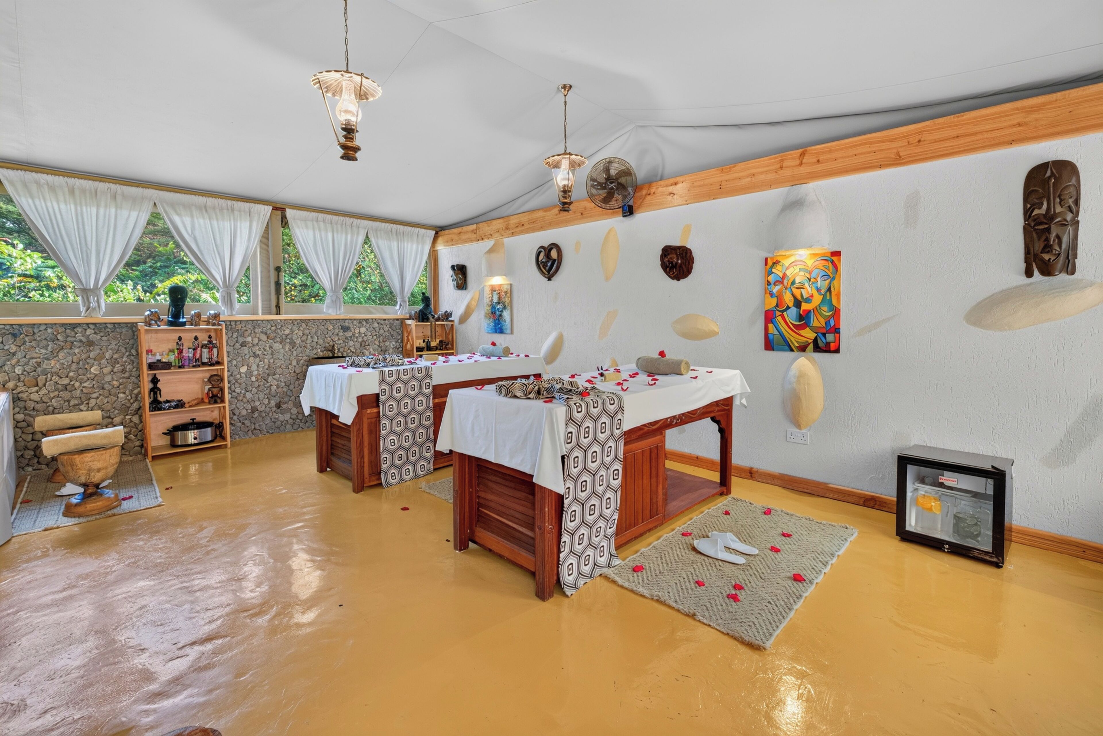 Une pièce avec une table en bois, un mur en pierre et une fenêtre avec des rideaux.
