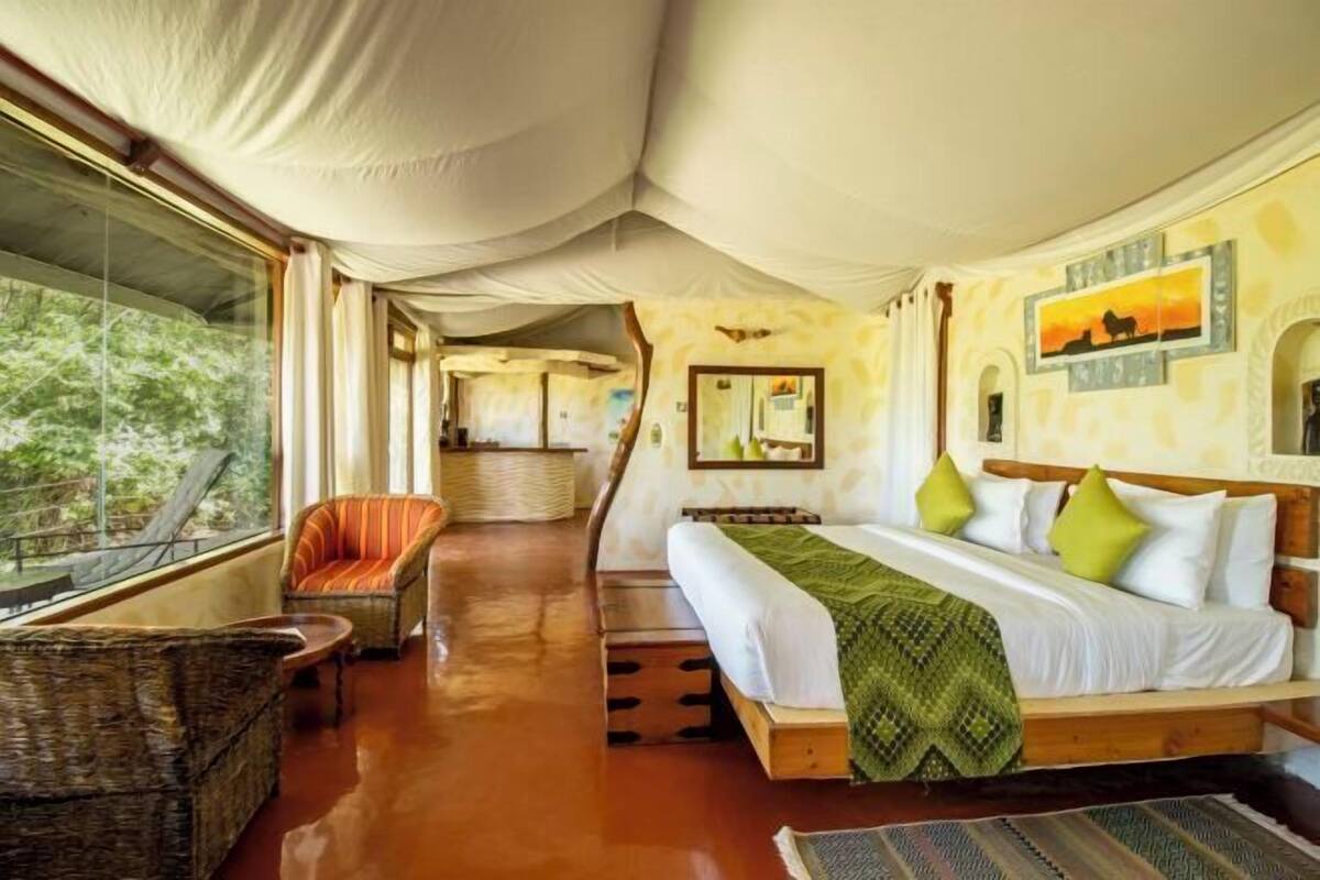 Una habitación con una cama, una silla, un ventanal y un espejo.