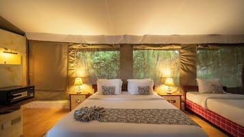 A tented room with two beds, each with a pillow and a lamp.