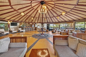 A spacious lounge area with a high ceiling and a central chandelier, surrounded by comfortable seating and a bar area. - PrideInn Mara Camp & Cottages (Maasai Mara)