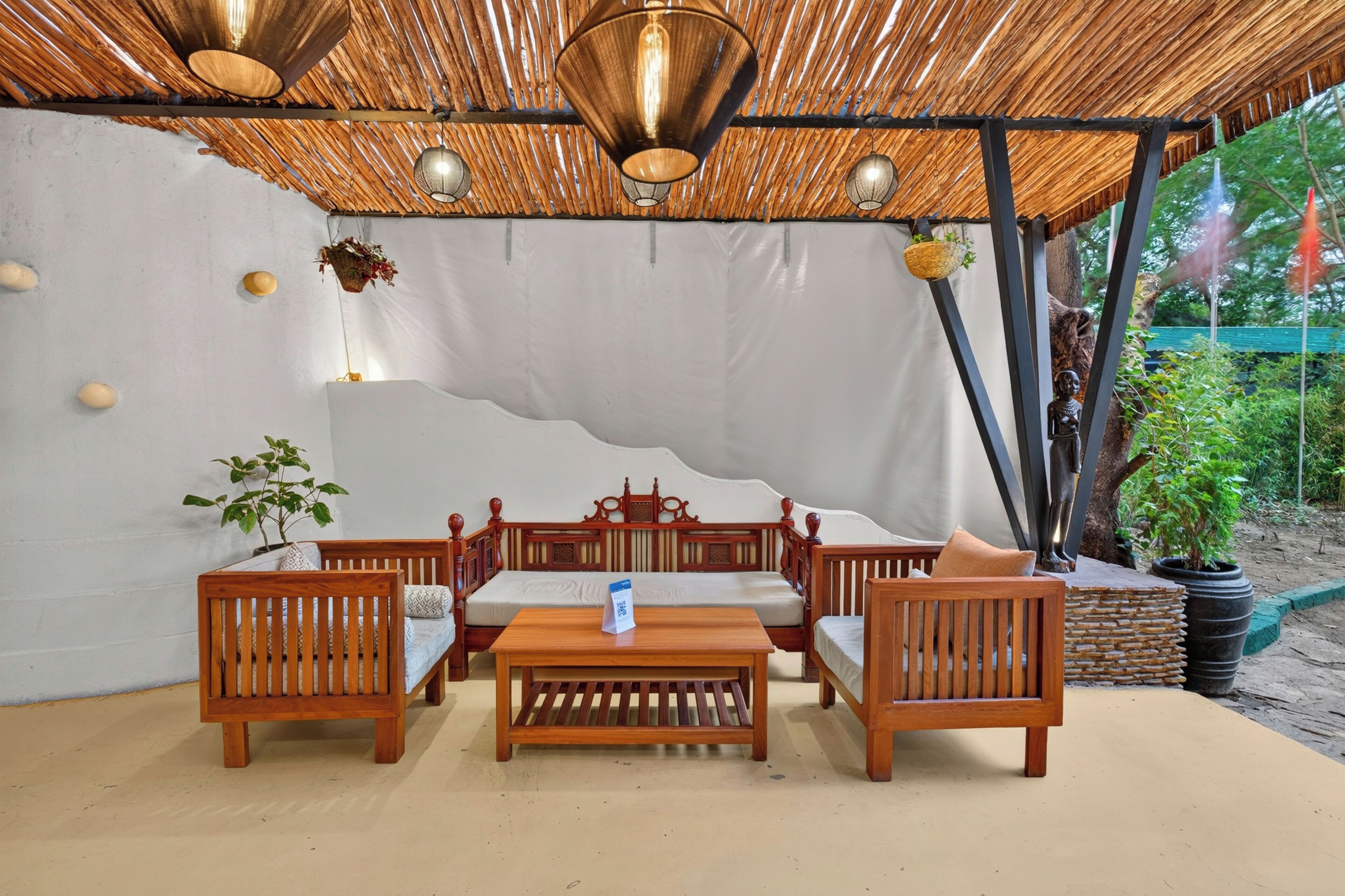 A covered outdoor seating area with a table and chairs, a hanging light fixture, and a wall with a unique texture.