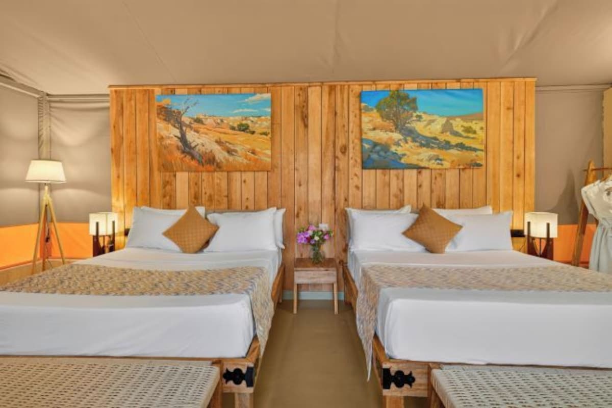 A double room with two beds, wooden paneling, and paintings on the walls.