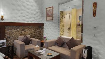 A living room with a stone fireplace, two sofas, a coffee table, and a small table with a bottle and tissues.