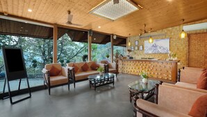A spacious lounge area with a wooden ceiling, large windows, and a reception desk.
