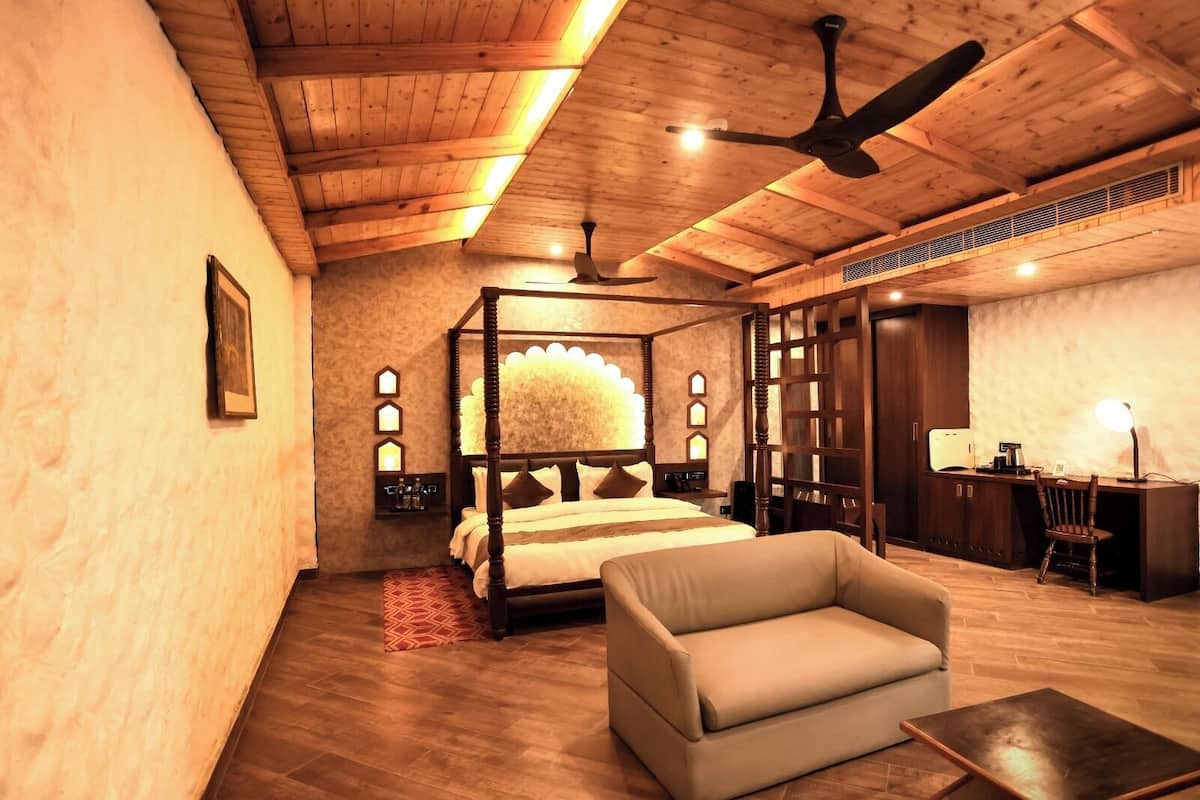 Um quarto espaçoso com uma cama de dossel, um sofá, uma escrivaninha e um ventilador de teto.
