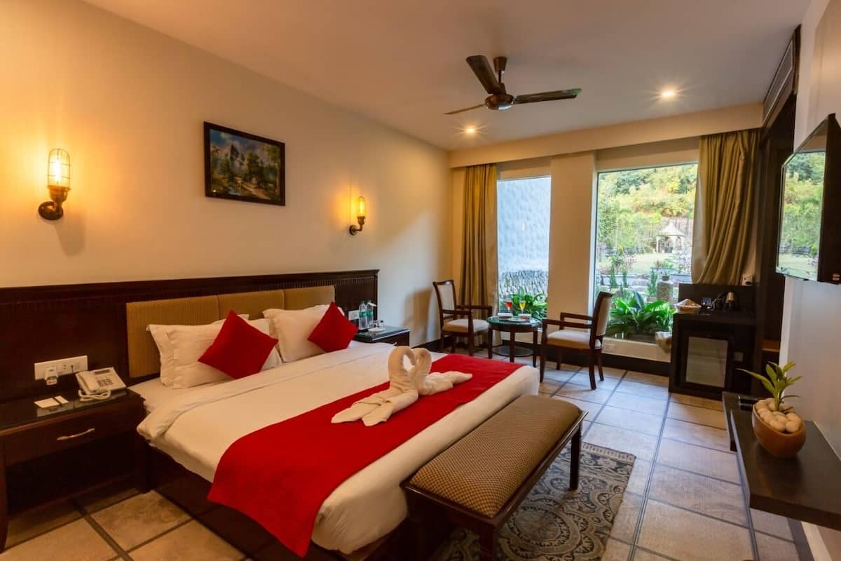 Quarto de hotel com cama, mesa de cabeceira, abajur e vista para o exterior.