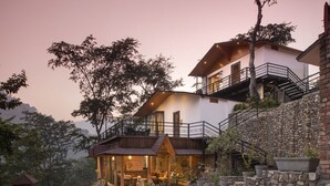 A two-story house with a stone facade, a wooden deck, and a balcony.