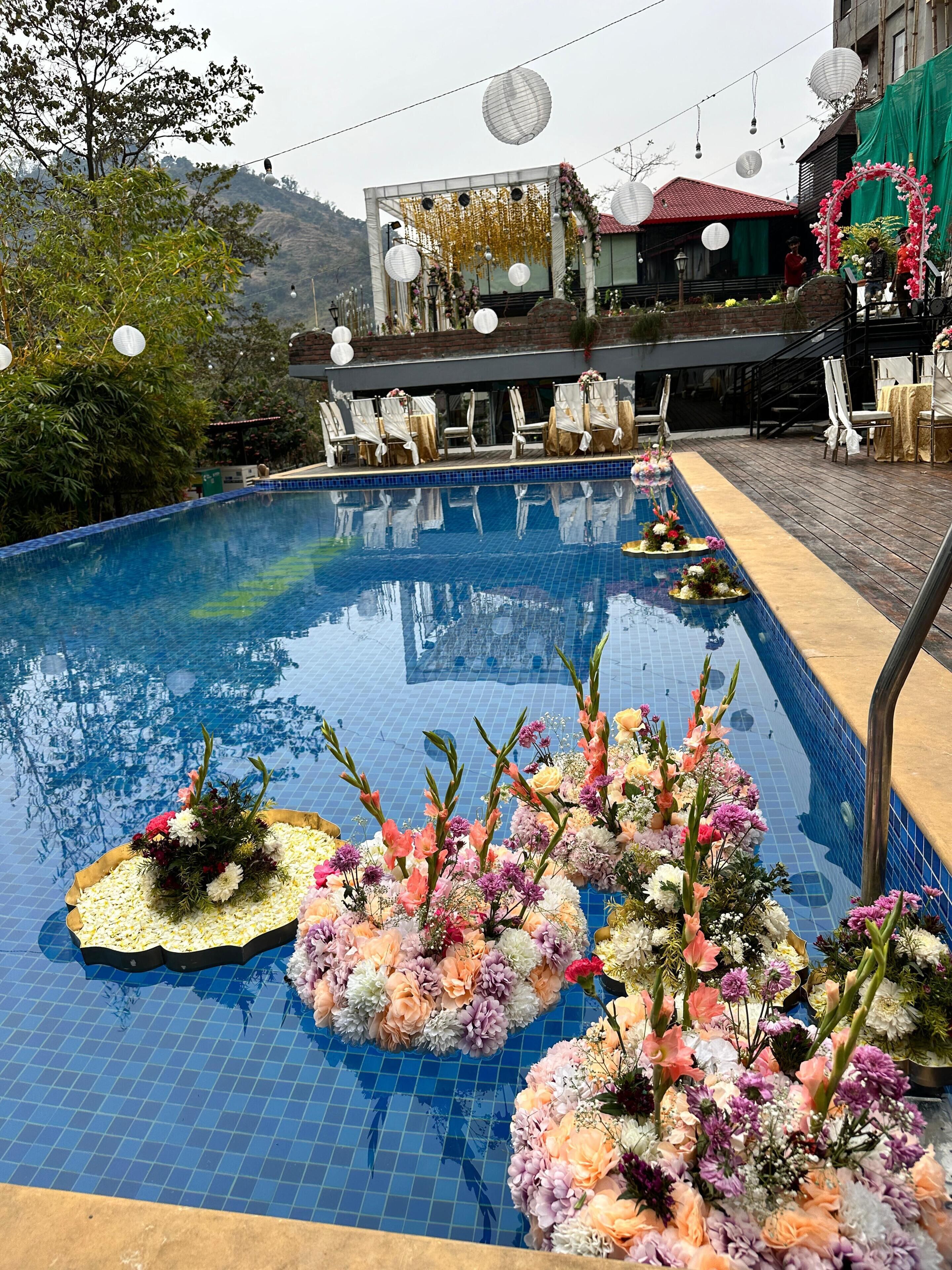 A swimming pool with floral arrangements and outdoor seating.