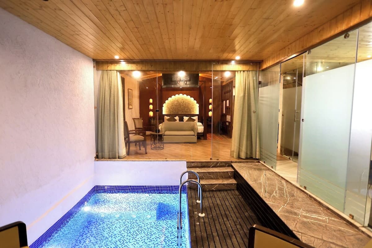 Uma área de spa com hidromassagem, um espaço de estar com sofá e poltronas, e teto de madeira.
