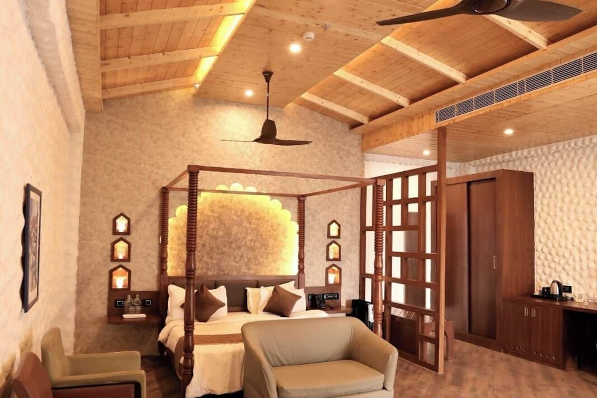 Um quarto amplo com uma cama grande, área de estar e espaço para trabalho.