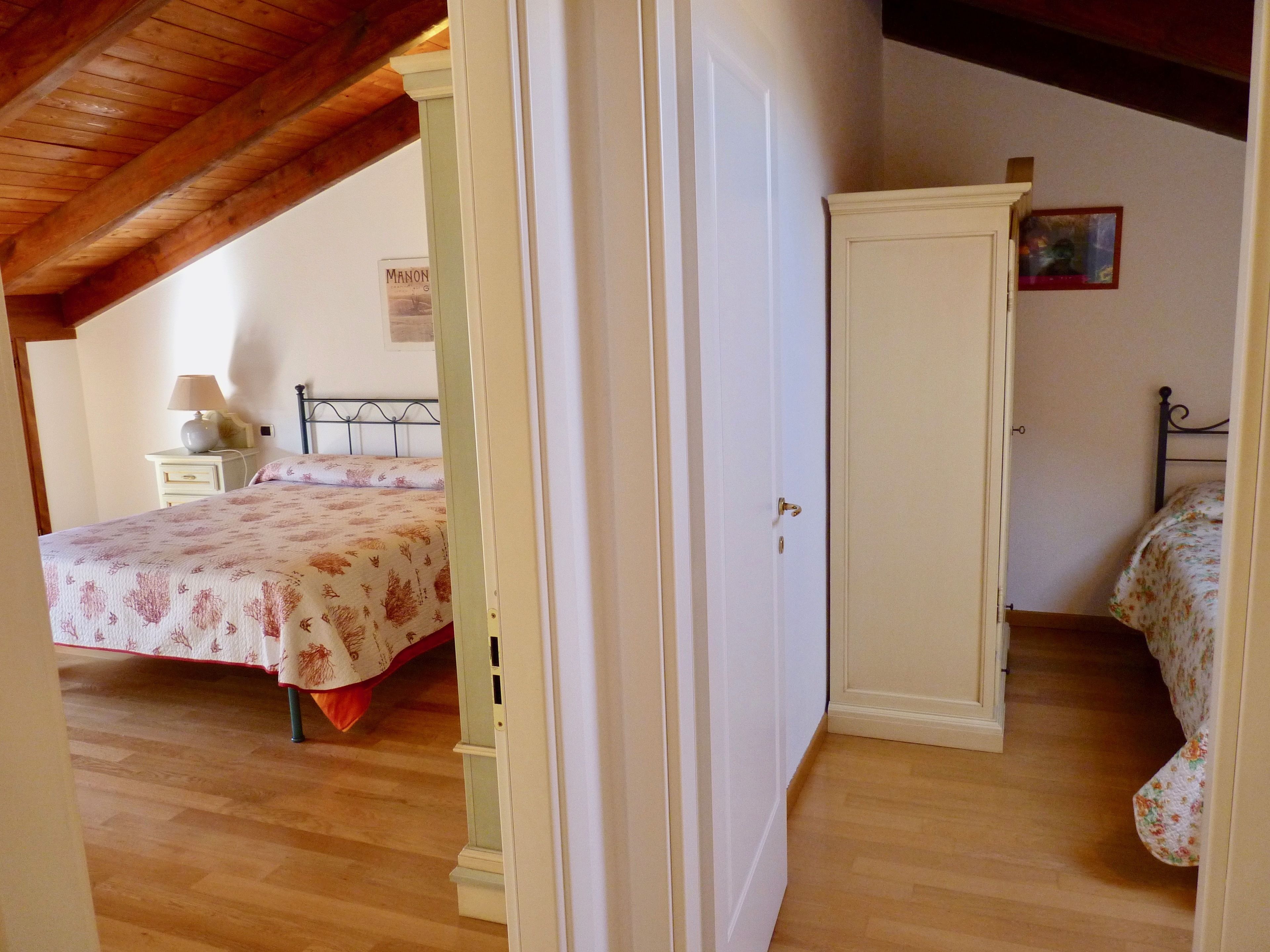 A bedroom with a bed, a nightstand, a wardrobe, and a wooden ceiling.