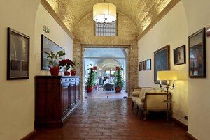 Un corridoio con pavimento in mattoni, archi in pietra e opere d'arte incorniciate alle pareti.
