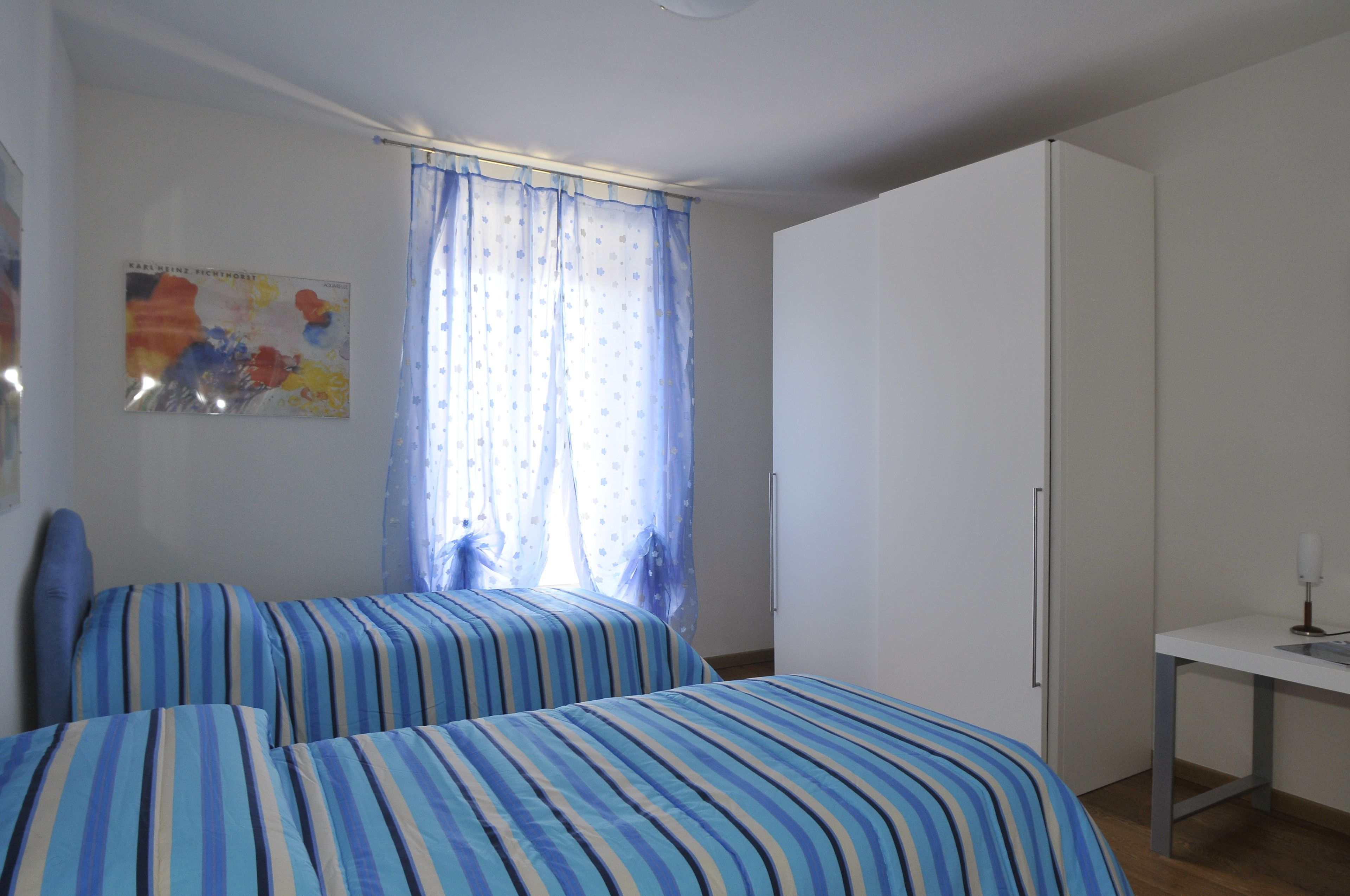 Ein Schlafzimmer mit zwei Betten, einem Schreibtisch und einem Kleiderschrank.