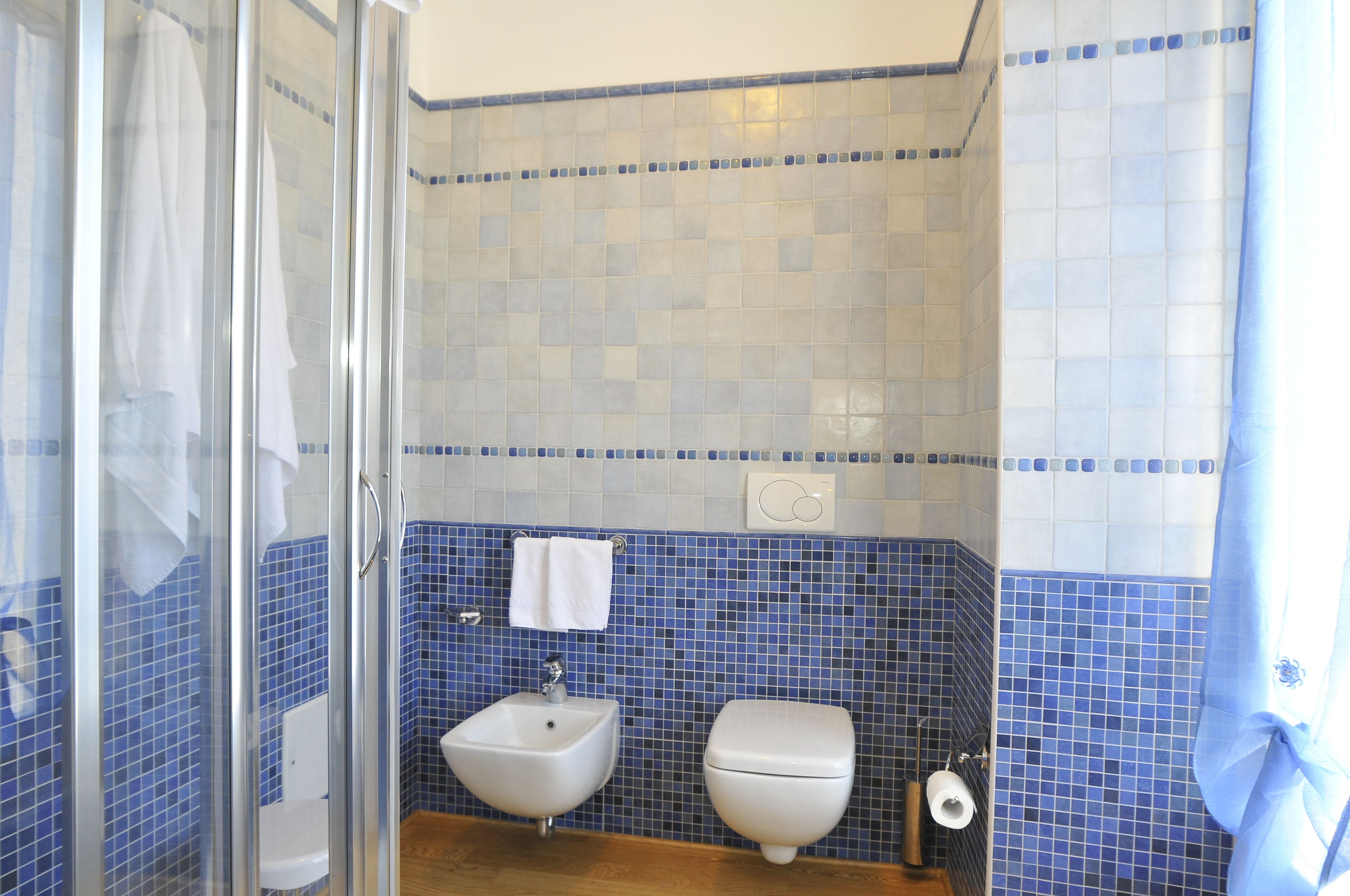 A bathroom with a glass shower enclosure, a sink, and a toilet.