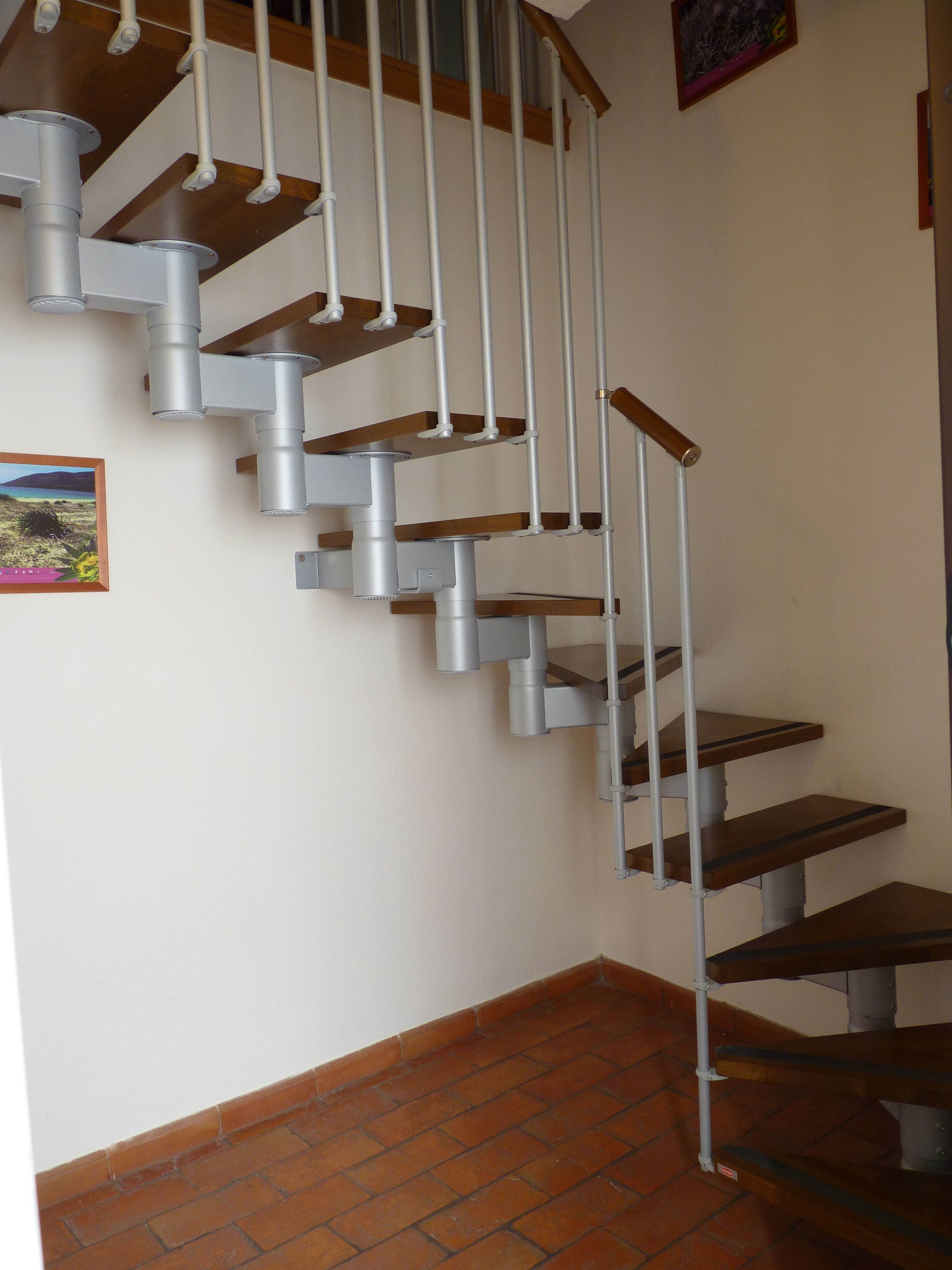 Una escalera de caracol con barandillas de metal y escalones de madera, que conduce a un piso superior.