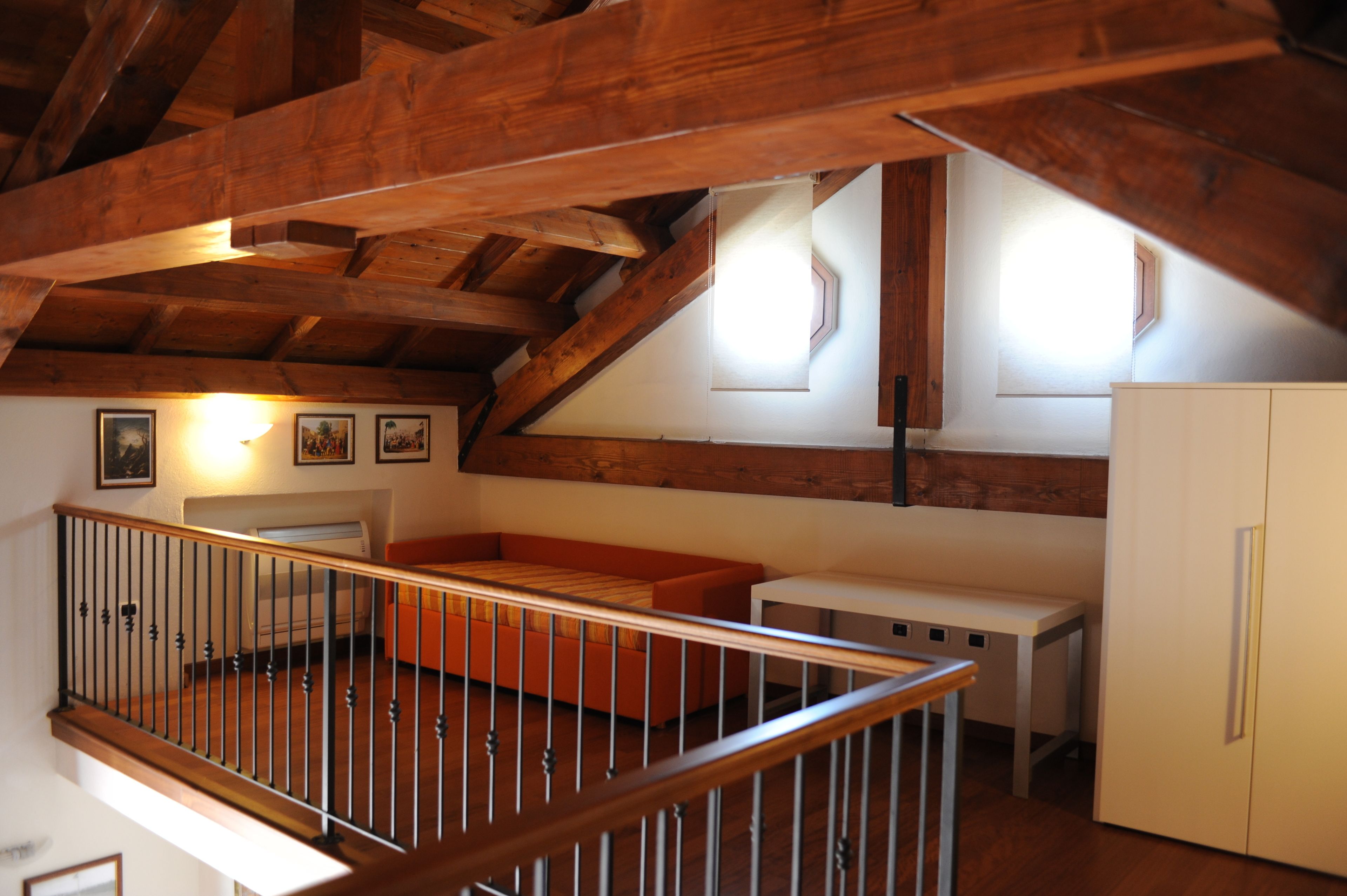 Ein Loft-Zimmer mit Holzbalken, einer Couch, einem kleinen Tisch und einem Schrank.