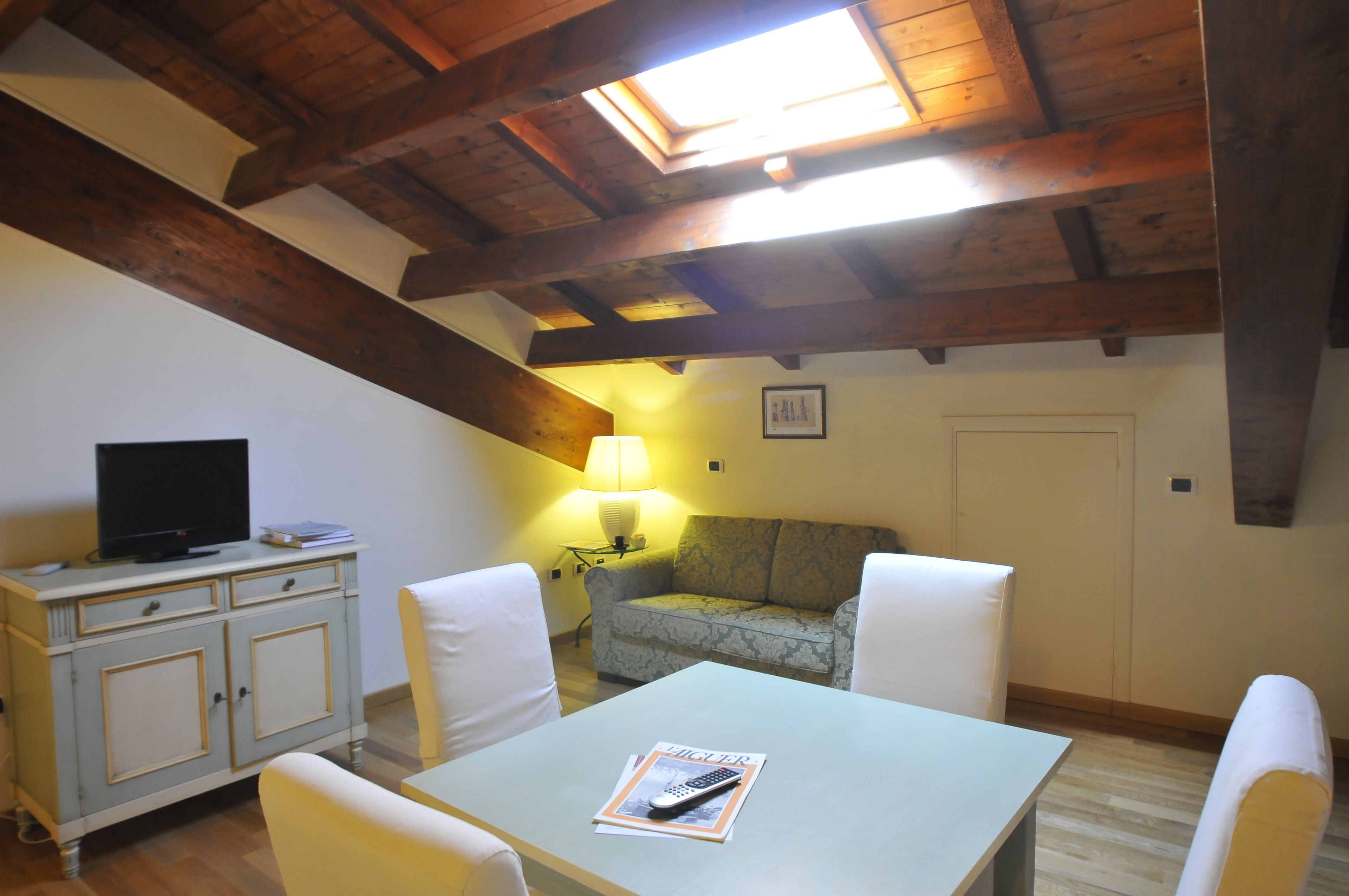 Une pièce chaleureuse avec un plafond en bois, un canapé, une table et un téléviseur posé sur un meuble.