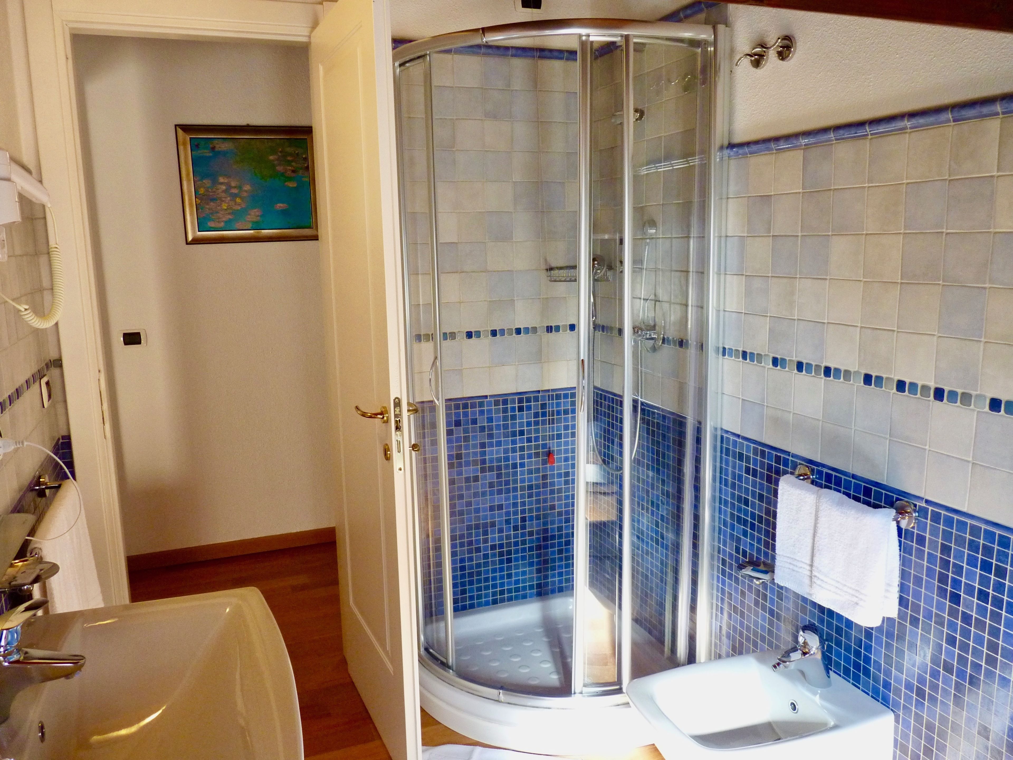 Baño con ducha envuelta en vidrio, lavamanos y retrete.
