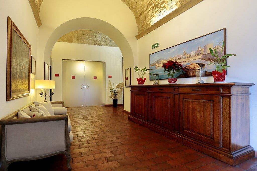 A lobby with a brick floor, a reception desk, a sofa, and a painting of a coastal scene.