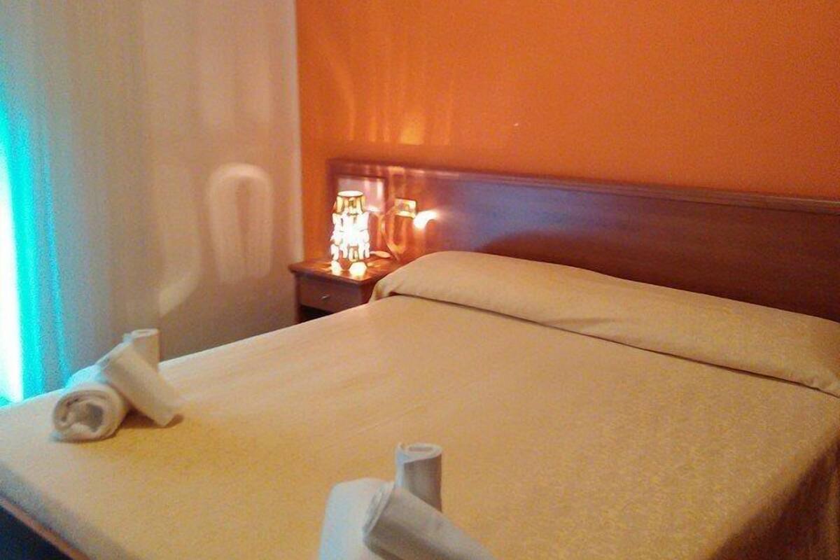 A hotel room with a bed, a nightstand with a lamp, and a painting on the wall.