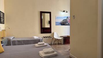 A hotel room with two beds, a desk, a chair, a mirror, and a painting on the wall.