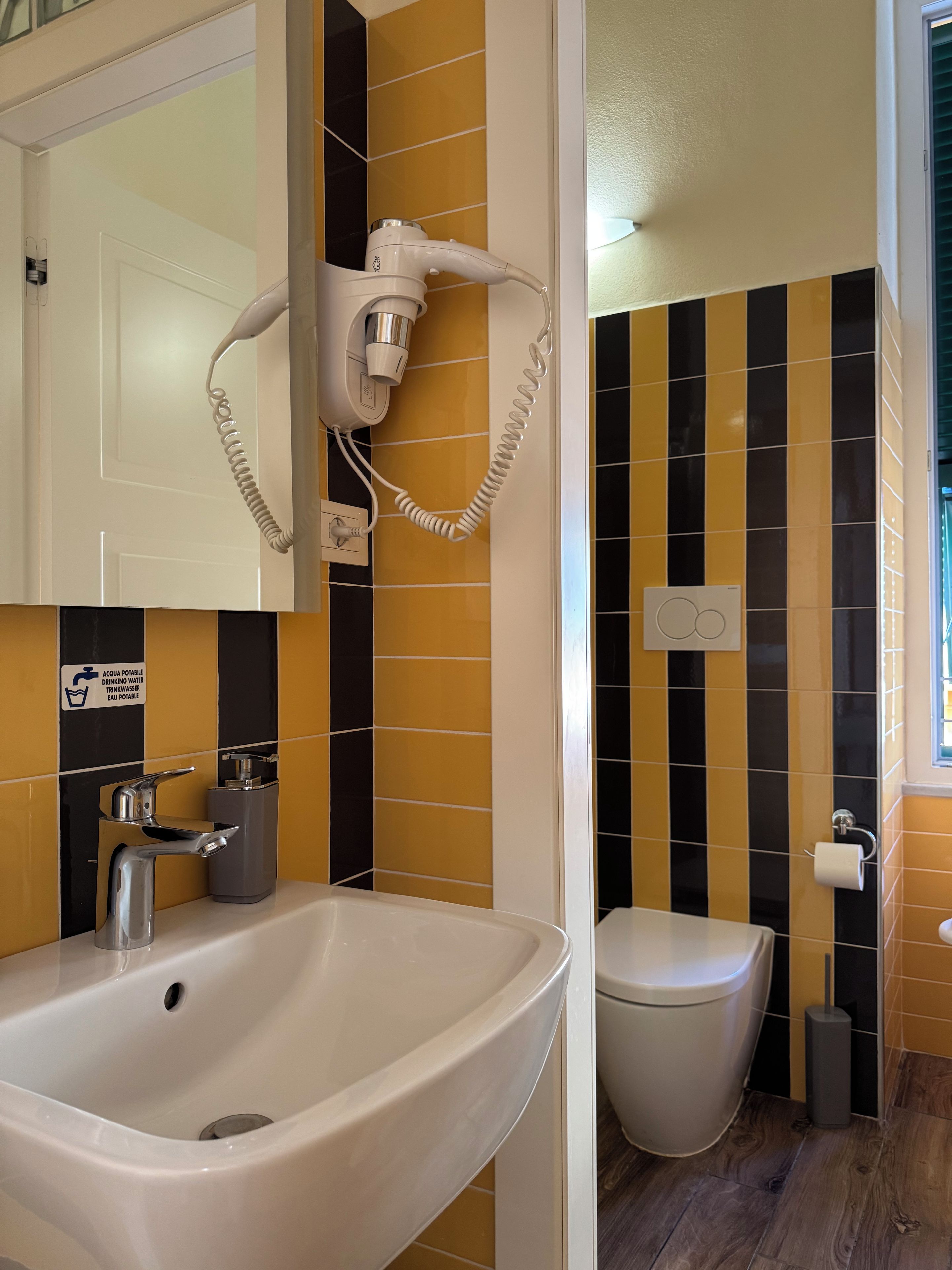 Een badkamer met een wastafel, toilet en een aan de muur bevestigde haardroger.