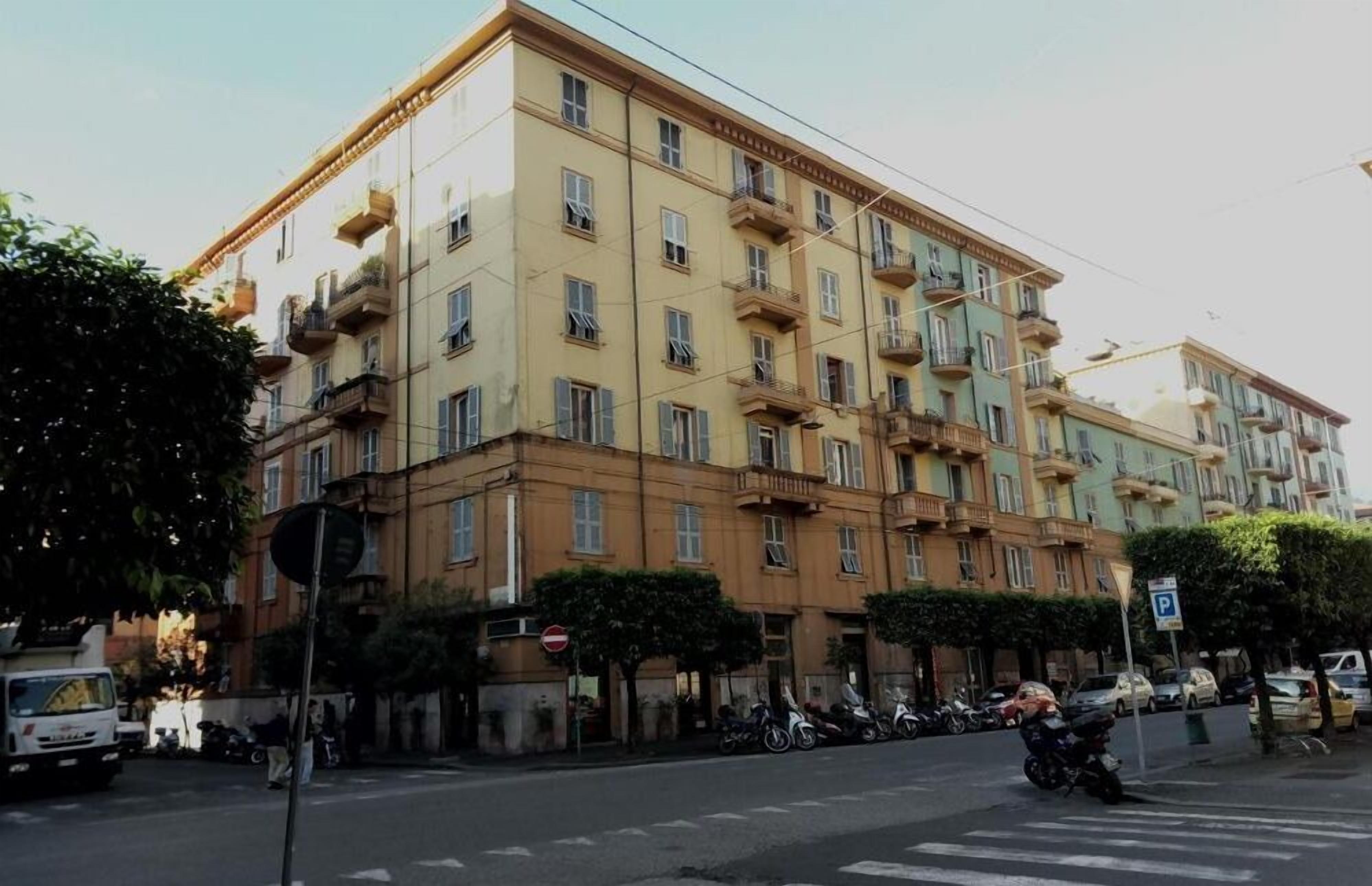 A multi-story building with balconies, parked motorcycles, and a street sign.